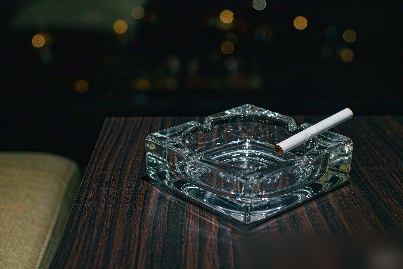 烟灰缸里搁着一支未点燃的香烟，夜间室内暖光